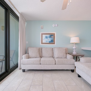 Relax in the airy living area featuring a sofa with queen sleeper, cozy seating, TV, and balcony on the beach