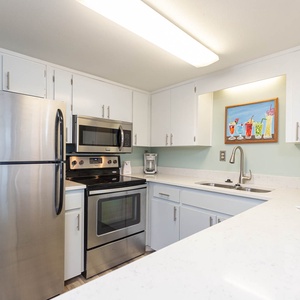 This kitchen features stainless steel appliances, white cabinetry, and a bright countertop, perfect for meal preparation