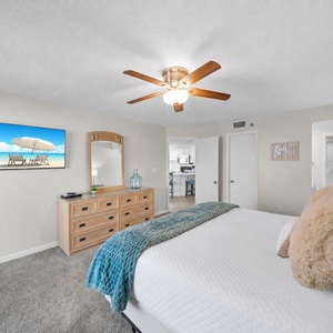 Relax in the master suite on the king bed with a cozy throw, a stylish dresser, and a wall-mounted TV