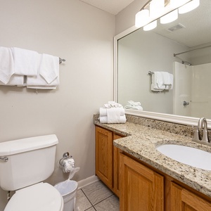 Brightly colored towels hang above a spacious countertop with an elegant sink in the guest bath with a tub/shower combo