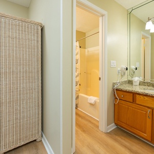 In the master bath, warm wood tones and polished counters invite you to refresh after a day at the shore