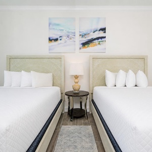 Tranquil guest bedroom featuring two queen beds with stylish headboards and soft linens for a restful stay