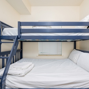 This cozy room features a blue bunk bed with a double bed below, perfect for families or friends sharing a fun getaway