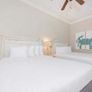 Guest bedroom featuring two cozy full beds, a charming crab artwork, and soft, neutral decor for a relaxing stay