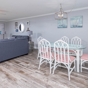 Enjoy meals at the glass dining table surrounded by inviting decor and a cozy living area with beach views