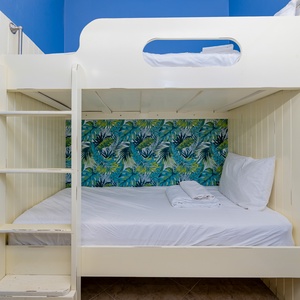 The colorful bunk room features vibrant tropical wallpaper and comfortable bedding, perfect for kids or extra guests