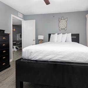 This cozy guest bedroom features a sleek black queen bed, ample storage, and a lovely view through the window