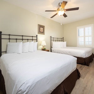 Rest comfortably in this inviting guest bedroom featuring two queen beds, tasteful decor, and natural light from the window