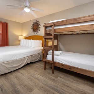 Cozy guest bedroom featuring a plush king bed alongside a wooden twin bunk bed, accented by warm orange curtains