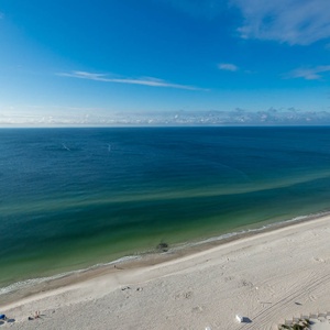 This stunning beachfront view showcases the tranquil blue waters and soft sands, perfect for a relaxing getaway