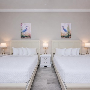Unwind in this guest bedroom with queen beds, soft linens, and coastal artwork