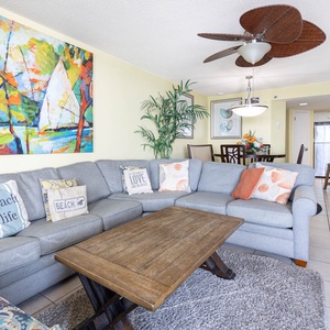 Vibrant living area features a cozy sectional sofa, rustic coffee table, and a dining space with floral accents