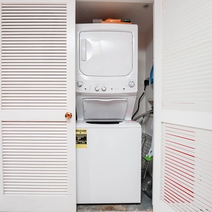 The laundry area features a stacked washer and dryer behind louvered doors, complemented by a vibrant red accent wall