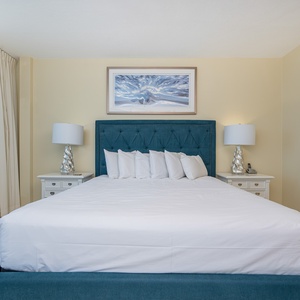 The master bedroom features a plush teal headboard, bright white bedding, and elegant lighting, perfect for relaxation