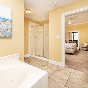 Inviting master bathroom featuring a jetted tub and a walk-in shower, with a view into a cozy bedroom