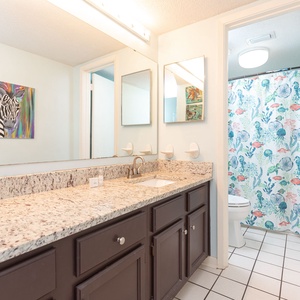 The master bath features a stylish granite countertop, vibrant floral shower curtain, and modern fixtures