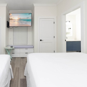 Cozy guest bedroom with two queen beds, a TV for entertainment, and a convenient reading nook