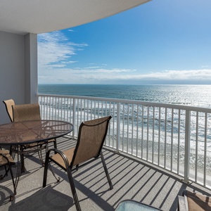 This balcony features a round table and four chairs, perfect for enjoying stunning views of the beach