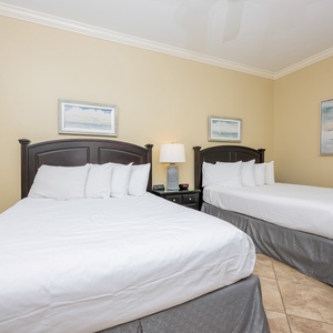 This guest bedroom features two comfortable full beds, soft white linens, and calming artwork, perfect for a relaxing stay
