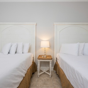 Rest comfortably in this guest room featuring two queen beds and a bedside lamp for a warm, relaxing atmosphere