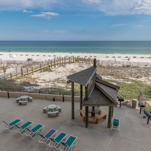 Beachfront pool area with a gazebo, picnic tables, and lounge chairs overlooking the tranquil waters