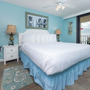 Turquoise walls complement the master suite, while sliding glass doors reveal the balcony with a serene beach front view