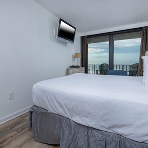 This inviting bedroom features a comfortable bed with a stunning beachfront view from the large windows