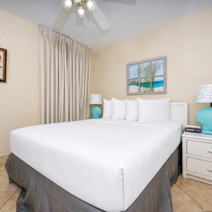 Cozy guest bedroom featuring a queen bed, beach-themed decor, and soft natural light from the window