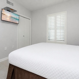 Relax in the comfortable guest room, featuring a queen bed, a TV for entertainment, and natural light from the window