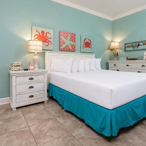 This bright guest bedroom features a king bed, aqua accents, and cheerful coastal decor for a refreshing retreat