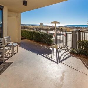 Patio to the pool features two chairs, offering a serene view of the beach front and easy access to outdoor amenities