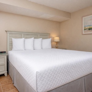 Guest bedroom with a queen bed, crisp linens, soft lighting, and beach-themed decor for a relaxing stay