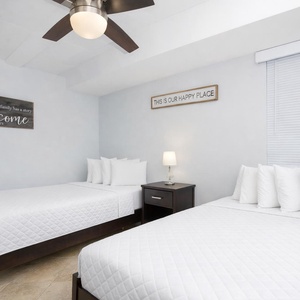 Inviting guest room featuring two comfortable beds, soft linens, and a warm welcome sign for a relaxing stay