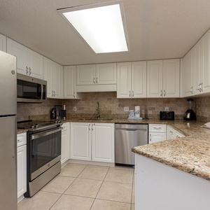 Bright kitchen with granite countertops, white cabinetry, and modern appliances, perfect for preparing meals during your stay