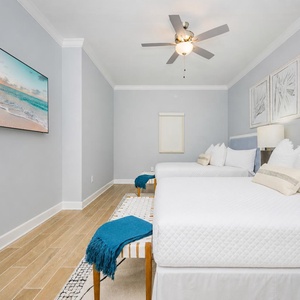 Inviting guest room featuring two cozy queen beds, coastal decor, and a large TV