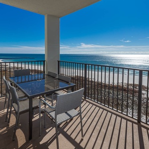 Balcony with a glass-top table and chairs offers a breathtaking view of the gulf and the white sand beach below