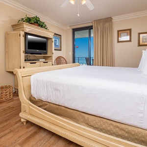 Relax in the inviting master bedroom featuring a king bed, a flat-screen TV, and soothing sounds of the beach