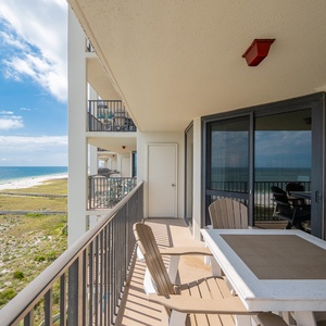 Spacious balcony features a dining table and chairs, offering a serene view of the beach and gulf beyond