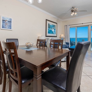 This dining area features a wooden table, stylish chairs, and a view of the beach through sliding glass doors