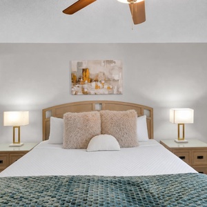 Serene master suite featuring a plush king bed with decorative pillows, soft lighting, and a calming abstract painting above