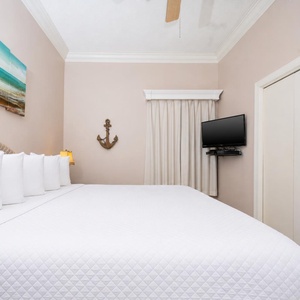 Relax in the inviting bedroom featuring a large bed, coastal decor, and a TV needs