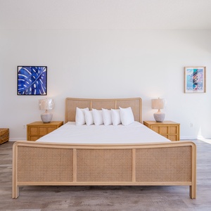 Master bedroom featuring a cozy king bed, stylish lamps, and breathtaking views through expansive windows and balcony doors