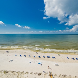 Enjoy the vibrant beach scene with colorful umbrellas and gentle waves, perfect for a relaxing day by the water