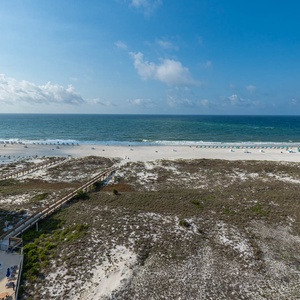 Expansive view of the beach with white sand, lounge chairs, and a clear blue sky, inviting relaxation and seaside enjoyment