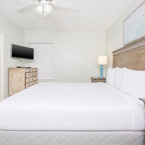 Cozy bedroom featuring a king bed, flat-screen TV, and soft pastel decor, creating a serene retreat for relaxation