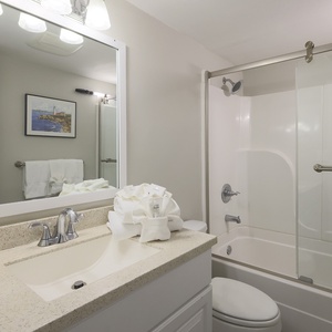 This bathroom features a sleek countertop, bright lighting, and a relaxing tub-shower combo for a refreshing experience