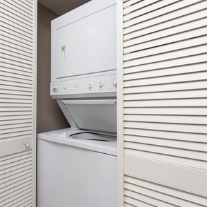 This laundry area features a stacked washer and dryer behind white louvered doors, providing convenience for guests