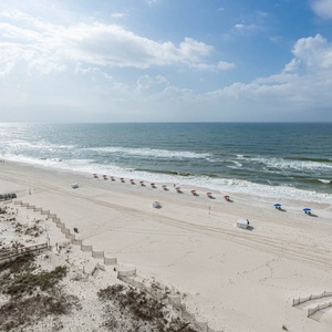 Gaze at the inviting shoreline, where beach chairs await your relaxation and the waves create a soothing backdrop