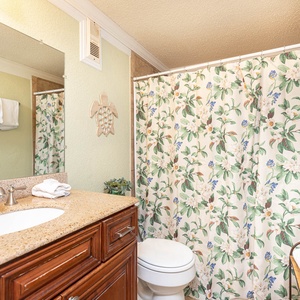 The bathroom features a stylish vanity, a spacious countertop, floral shower curtain, and fresh towels for your convenience