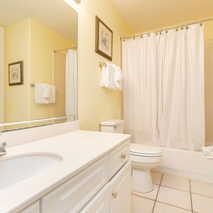 The master bathroom features a bright yellow hue, a spacious vanity, and a shower-tub combo, perfect for a refreshing retreat